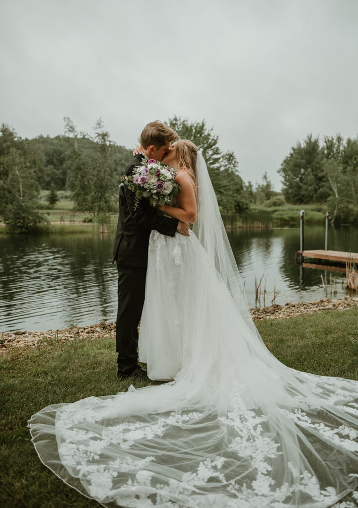 a bride and groom kissing on the edge of the pond at dixons apple orchard