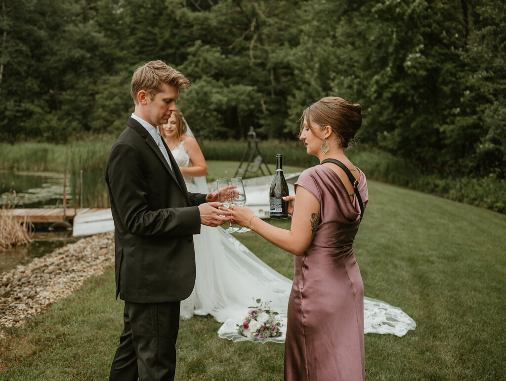 a bride's assistant passing off the champagne to the groom after the first look