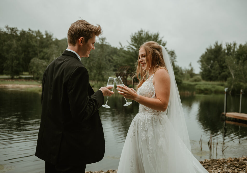 a bride and groom doing a champagne toast by the pond after their first look at dixons apple orchard