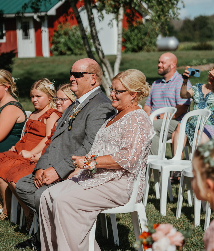 the grooms parents smiling in the crowd during his ceremony