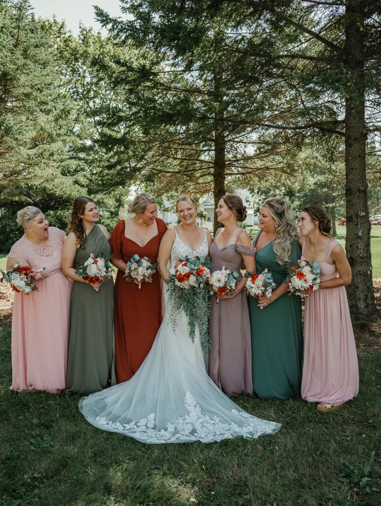 bride smiling with her bridesmaids in the wooded area at homestead meadows farm