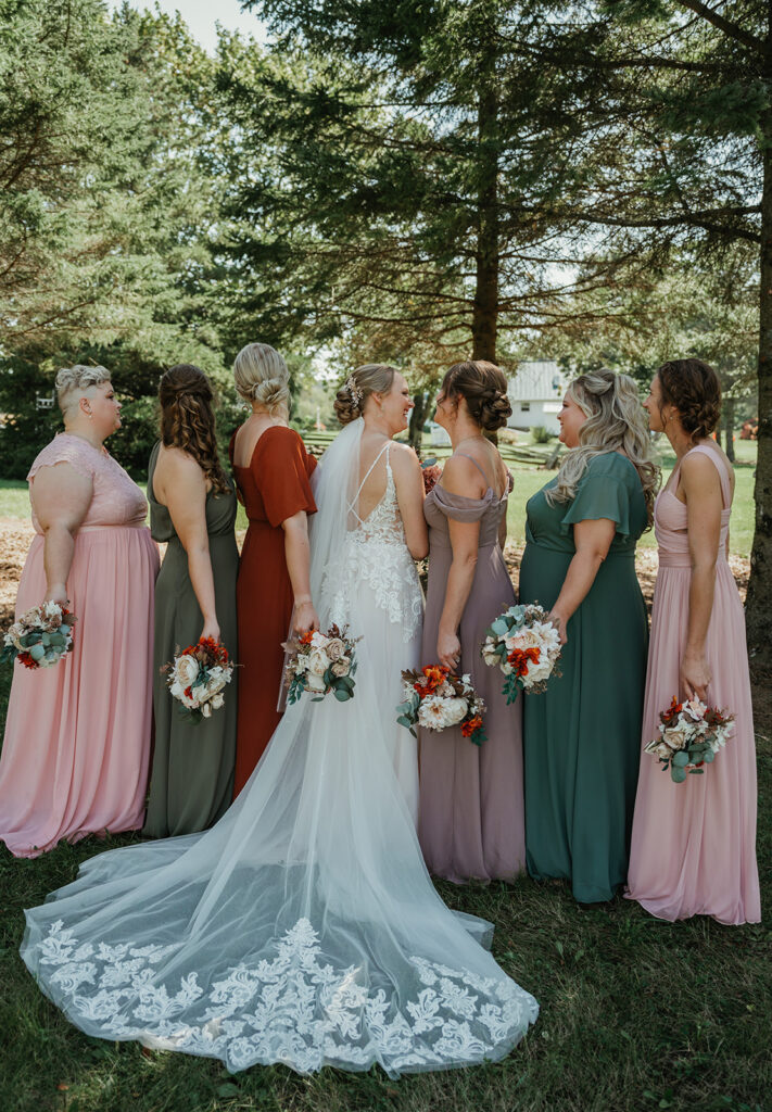 bride and her bridesmaids faced away from the camera smiling and laughing with each other