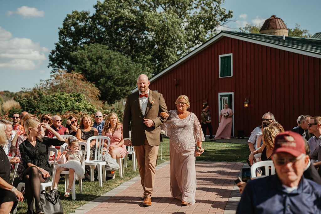 the groom and his mom walking down the isle 