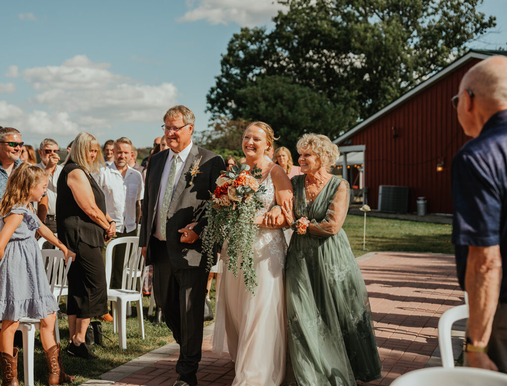 the bride and her parents walking down the isle