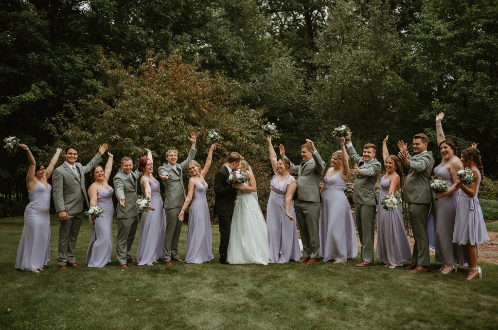 a bridal party surrounding the bride and groom cheering for them