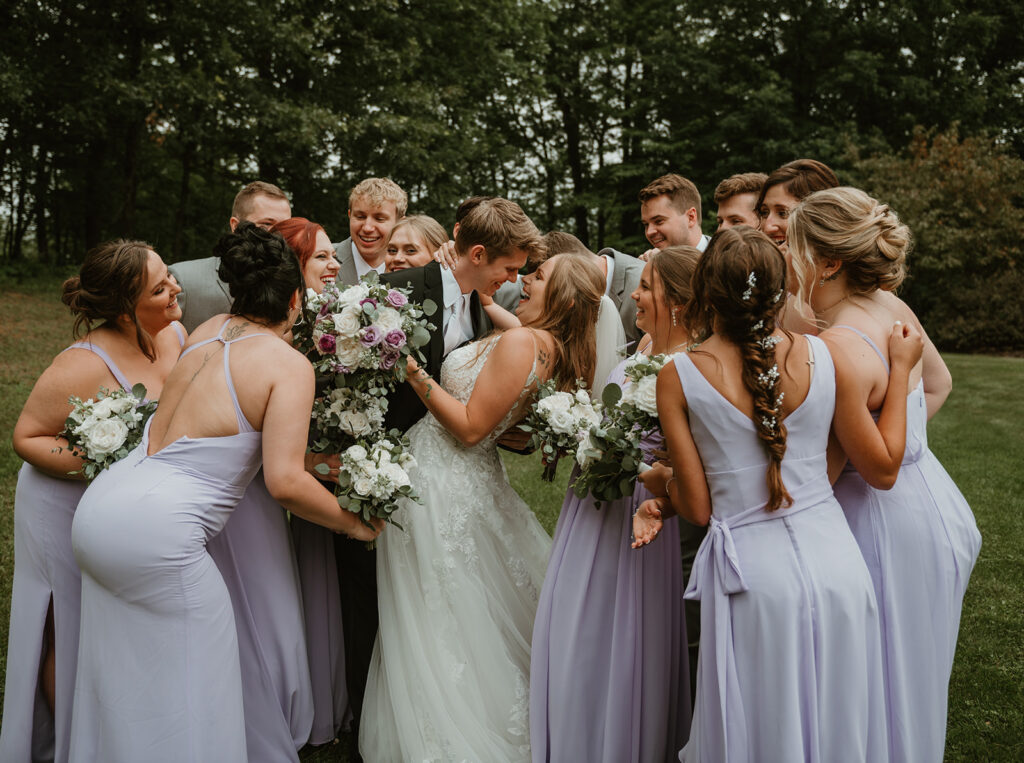 a bride and groom in the middle with their bridal party running in for a group hug