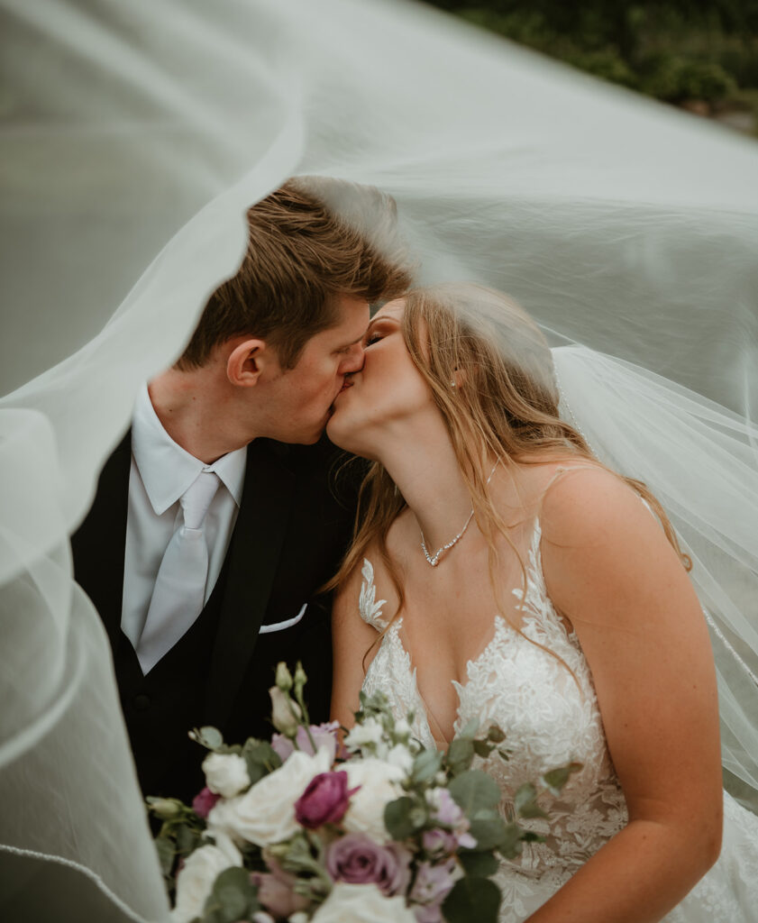 a bride and groom kissing under a veil 