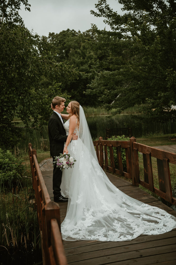 a bride and groom about to kiss on a bridge over the pond at dixons apple orchard