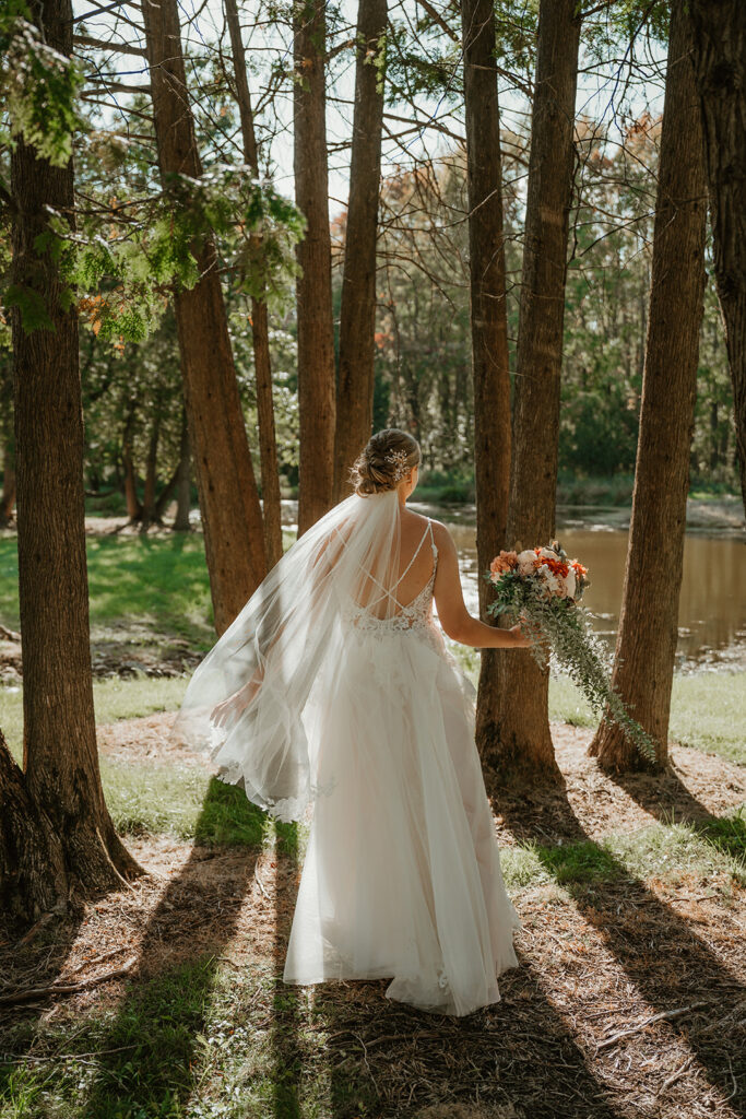 a beautiful bride on her wedding day surrounded by tall trees