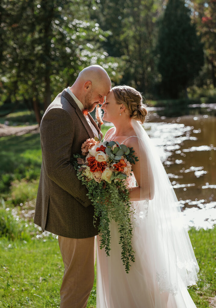 a bride and groom standing together near the lake at homestead meadows farm