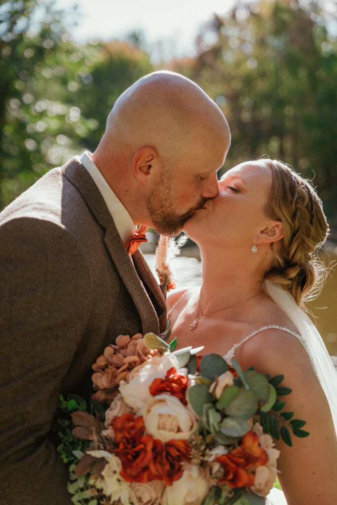 a bride and groom kissing on their wedding day with the sunshine shining down on them