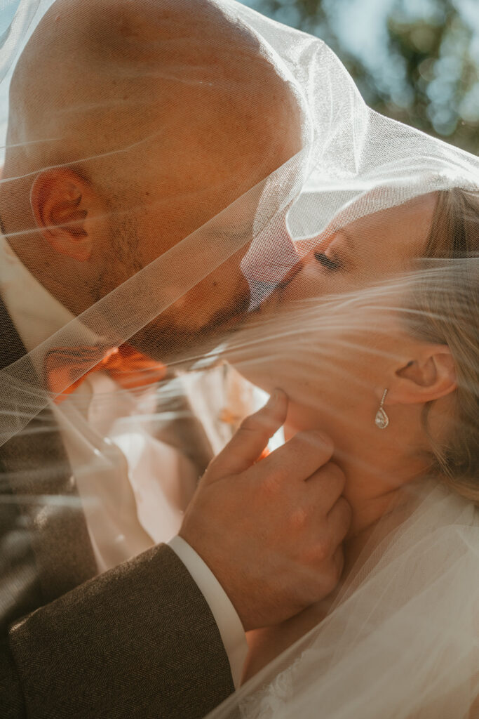 a bride and groom under a veil kissing