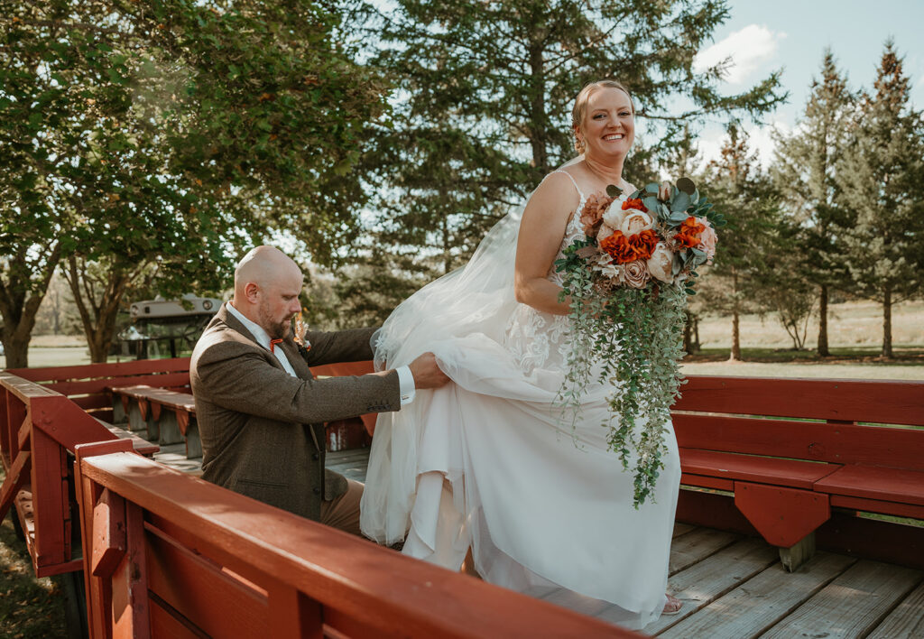 a groom helping his bride up onto the tractor wagon at homestead meadows farm