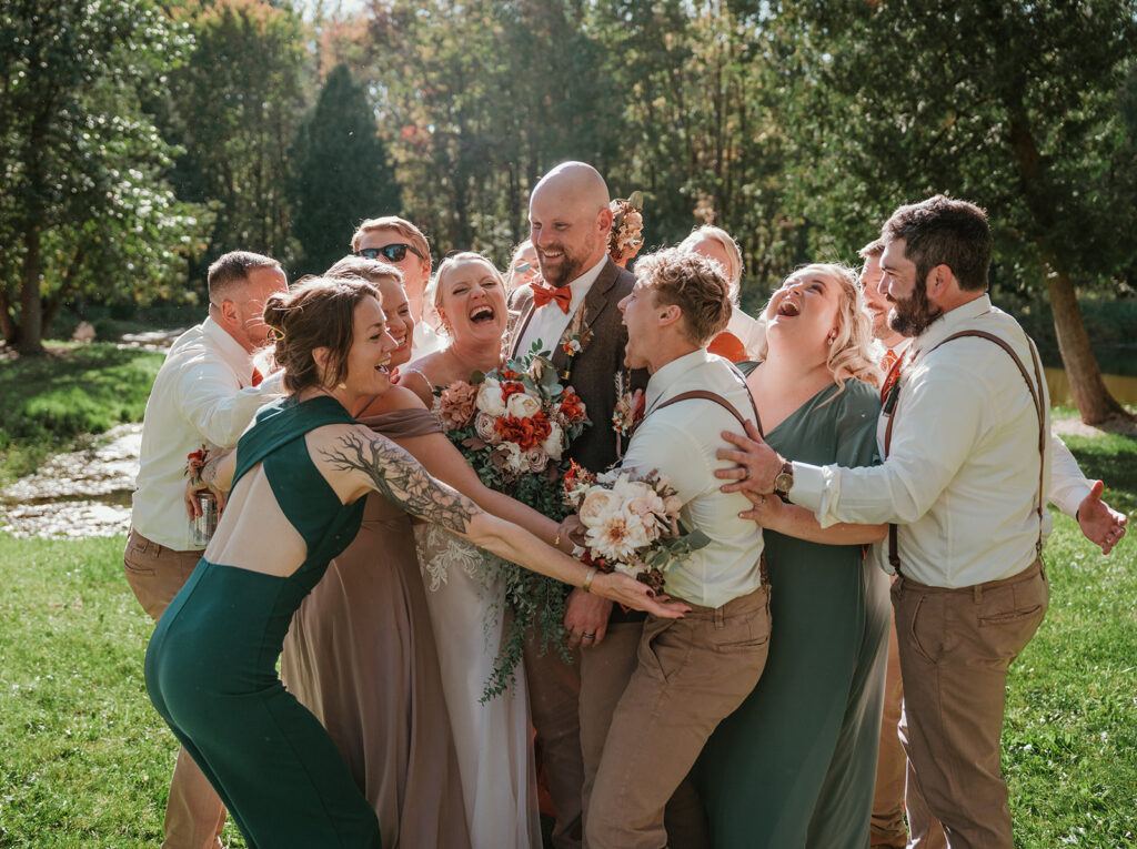 a bride and groom in the middle of a big group hug on their wedding day