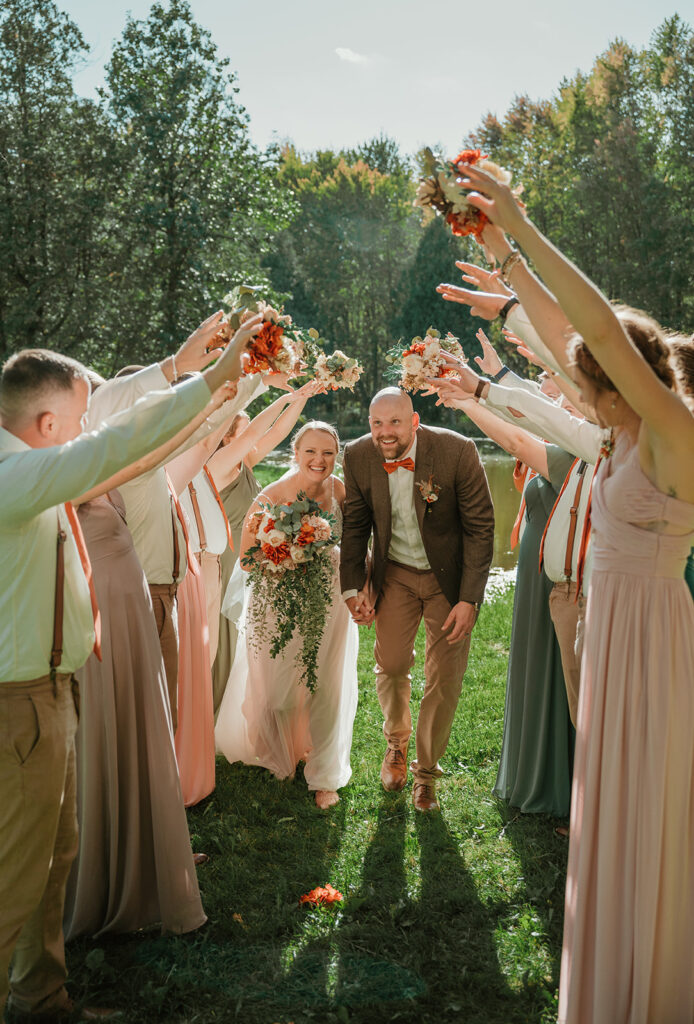 a bride and groom walking through a bridal party tunnel on their wedding day