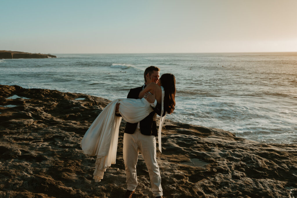 Candid moment of joy: eloping couple laughing together at Sunset Cliffs, capturing the natural emotion of their San Diego wedding